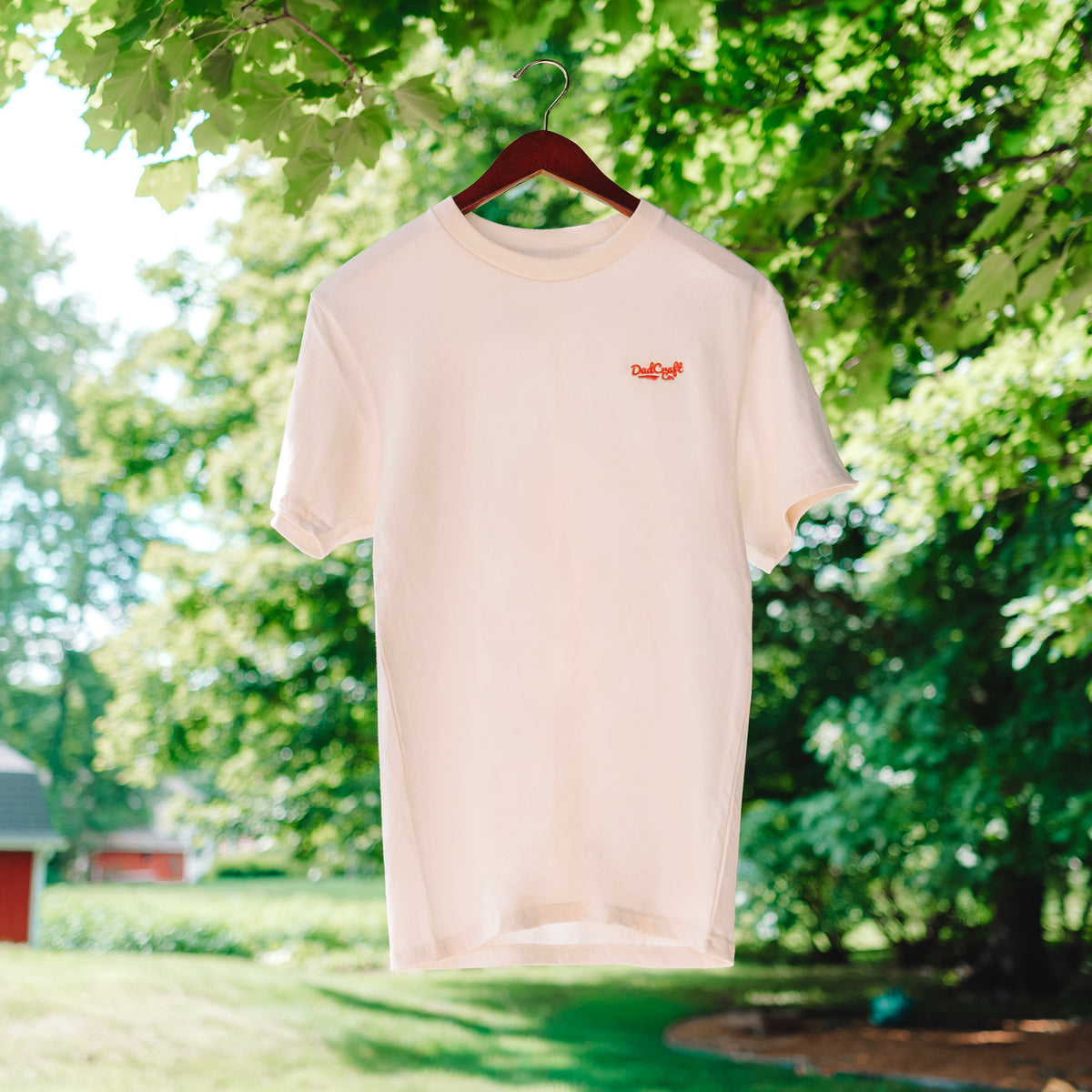 A Cream white T-Shirt with a small red DadCraft logo embroidered on the left chest